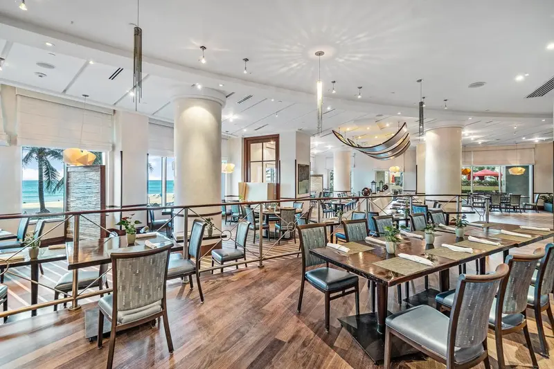 Une salle lumineuse avec des tables dressées pour un repas.