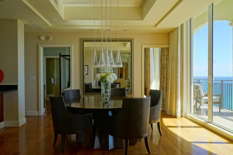 Une salle à manger lumineuse avec une grande table et un accès à un balcon avec vue sur la mer.