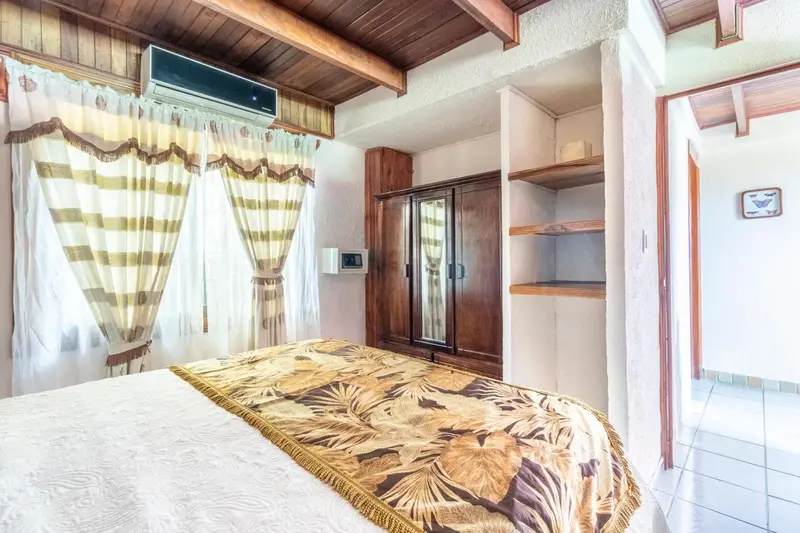 Une chambre lumineuse avec un lit recouvert d'une courtepointe à motifs et des rideaux décoratifs.