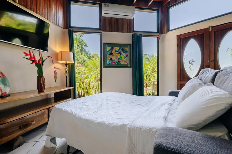 Une chambre lumineuse avec un grand lit et une vue sur la végétation.
