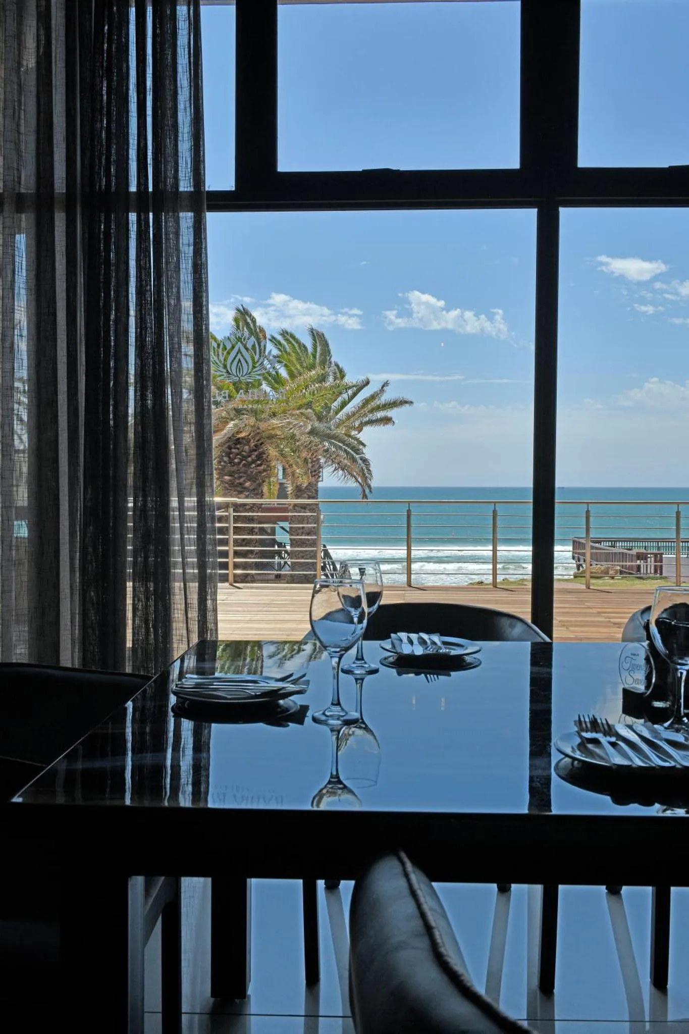 Une table dressée avec des verres et une vue sur la mer.