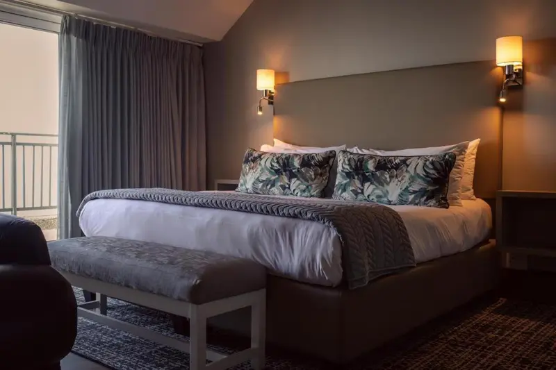 Une chambre avec un grand lit et une baie vitrée.