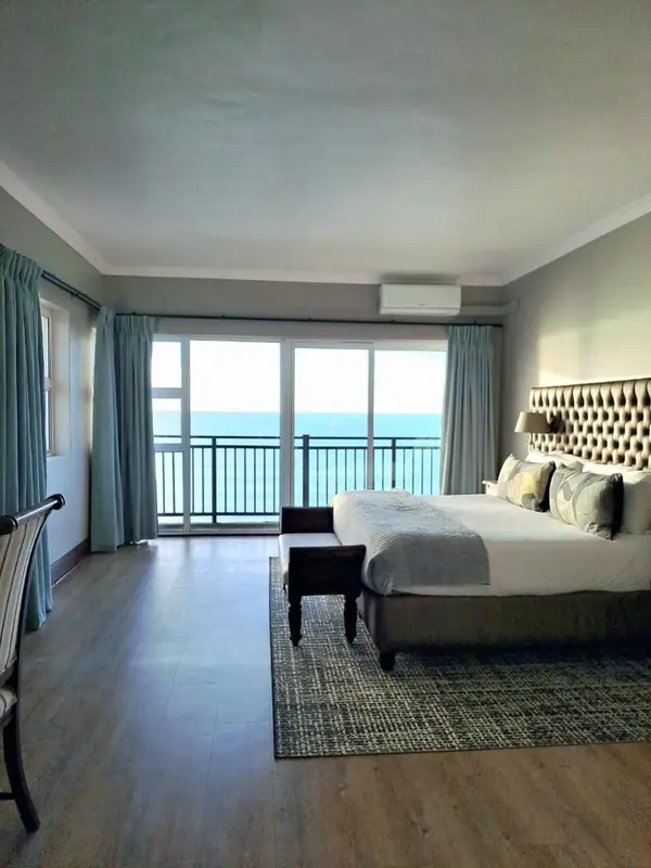 Une chambre lumineuse avec un grand lit et une vue sur la mer depuis un balcon.