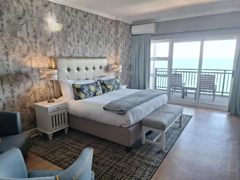 Une chambre lumineuse avec un grand lit et un accès à un balcon donnant sur la mer.