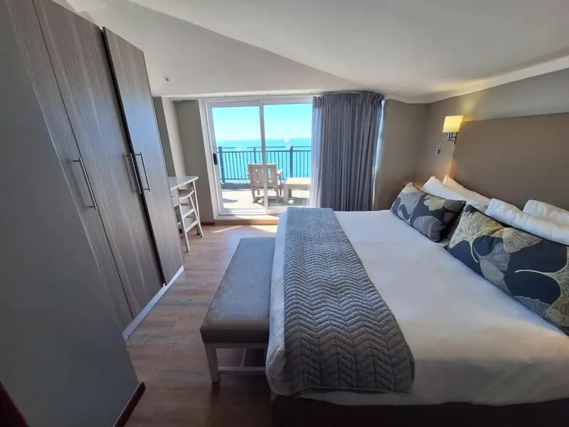Une chambre lumineuse avec un grand lit et un accès à une terrasse vue sur mer.