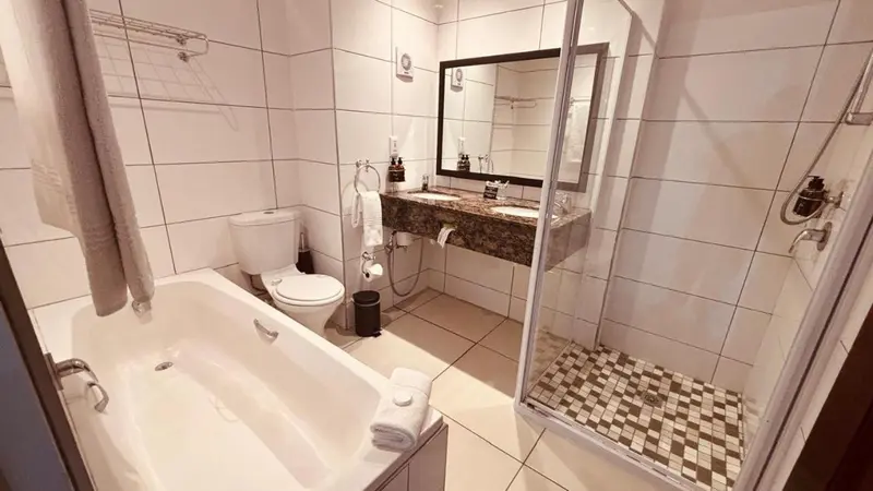 Une salle de bain claire avec baignoire et douche à l'italienne.