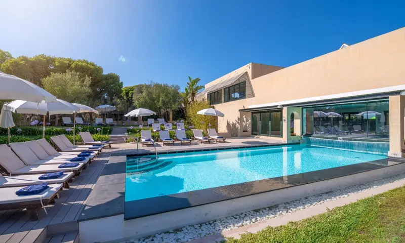 Transats bleus alignés au bord d'une piscine rectangulaire dans un jardin soigné.