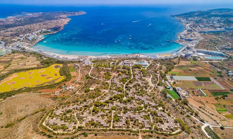 Vue aérienne d'une côte avec une plage et des bâtiments bas.