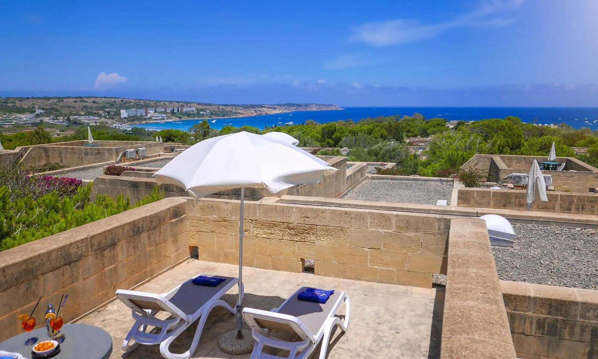 Terrasse avec transats et vue sur la mer et la côte.
