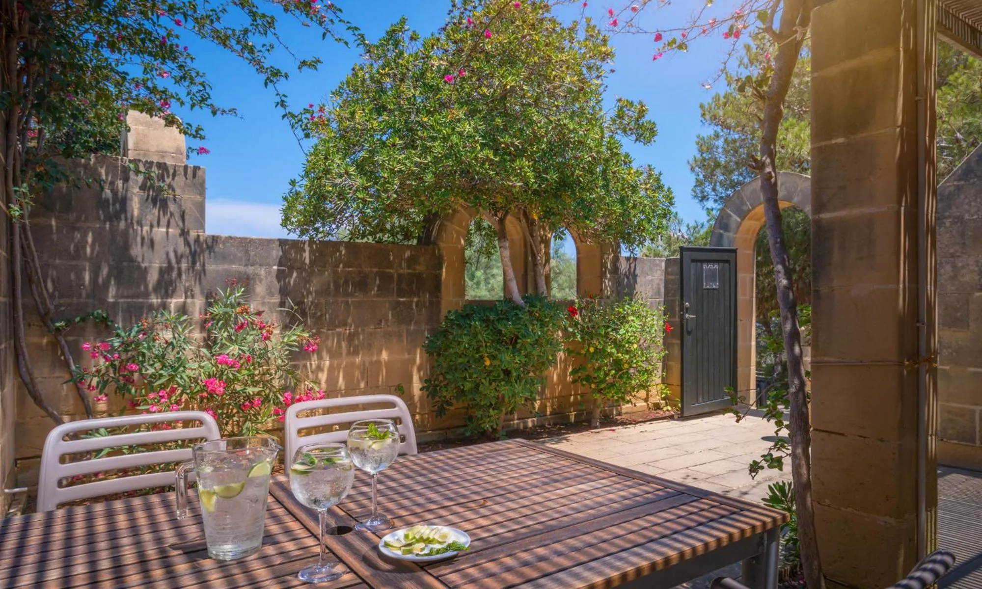 Une table avec des boissons et une assiette est placée dans une cour ombragée.