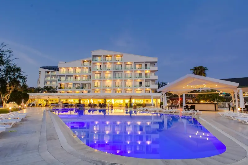 Bâtiment blanc illuminé avec piscine et mobilier d'extérieur.