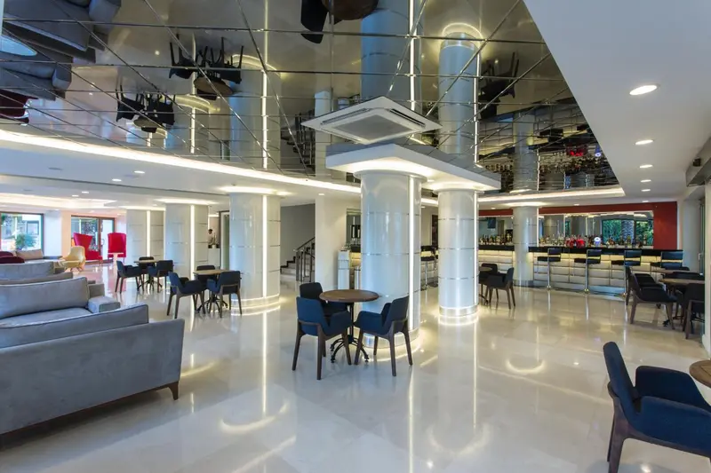 Espace de détente lumineux avec canapés, tables basses et comptoir de bar.