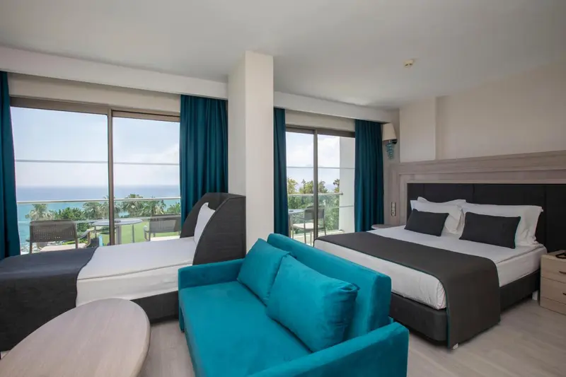 Une chambre avec un canapé bleu et une vue sur la mer par de grandes baies vitrées.