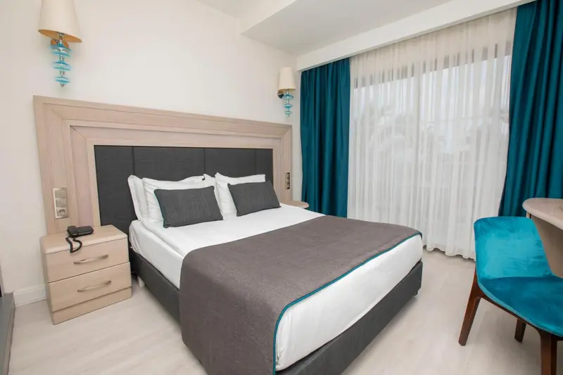 Une chambre lumineuse avec un grand lit et des rideaux turquoise.