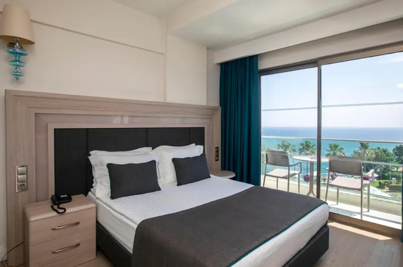 Une chambre lumineuse avec un grand lit donnant sur une vue mer.