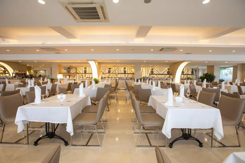 Une salle lumineuse et spacieuse est aménagée avec des tables dressées pour un repas.
