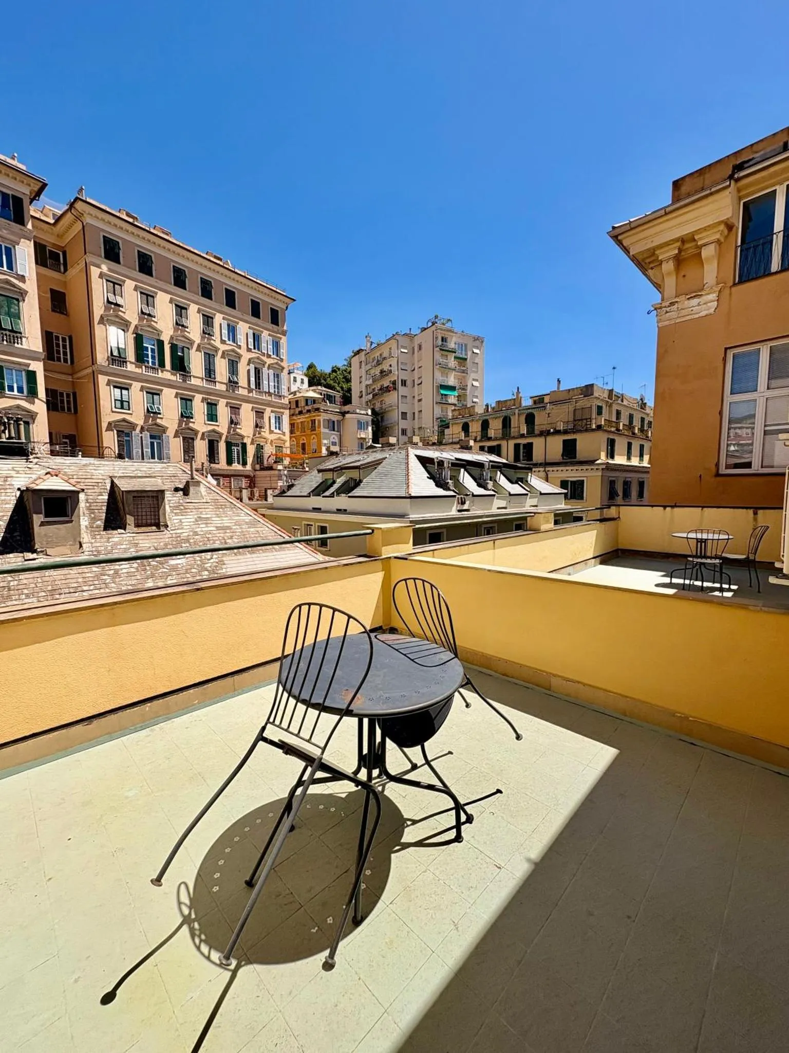 Terrasse ensoleillée avec mobilier de jardin et vue sur la ville.