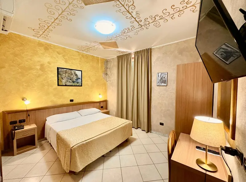 Une chambre lumineuse avec un lit double et un bureau.