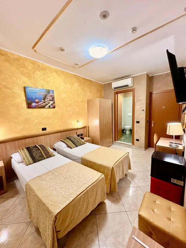 Chambre lumineuse avec deux lits simples et une décoration murale.