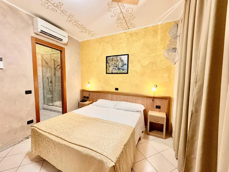 Chambre lumineuse avec un lit double et une salle de bain attenante.