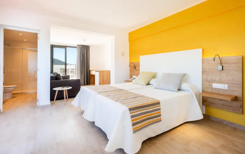 Une chambre lumineuse avec un grand lit et un espace salon.