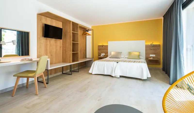 Une chambre lumineuse avec un lit double et un espace bureau.