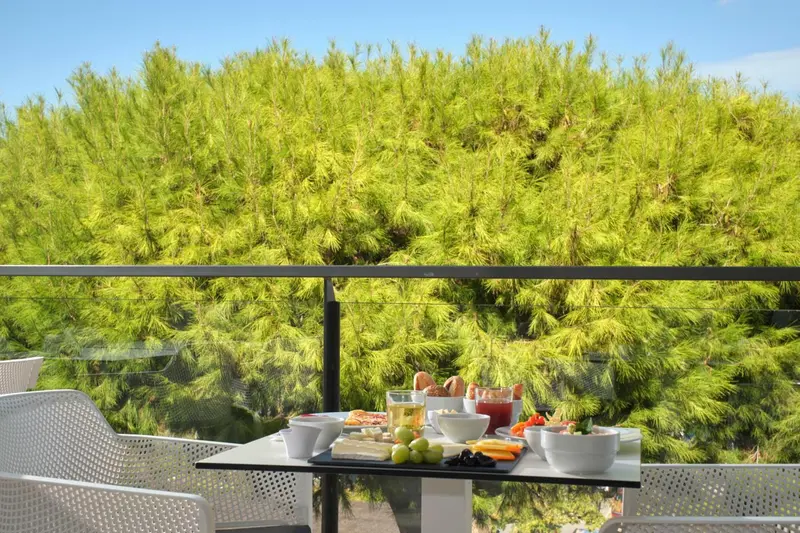 Une table de petit-déjeuner est dressée sur une terrasse ensoleillée.