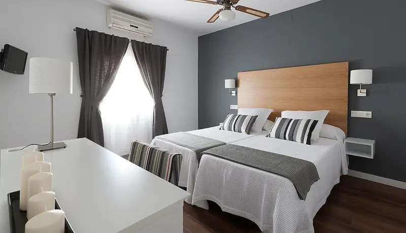 Une chambre avec deux lits simples et un bureau.