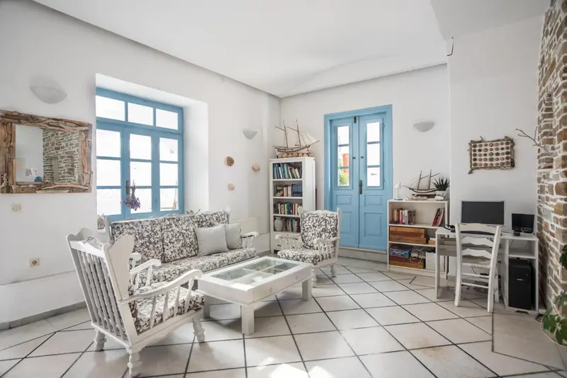 Interieur lumineux avec canape, fauteuils et etageres decoratives.