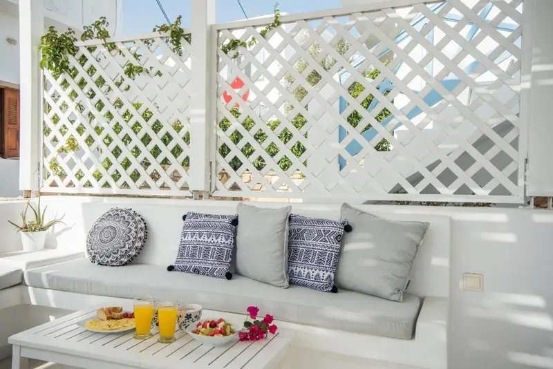 Canapé blanc et table basse sur une terrasse ombragée.