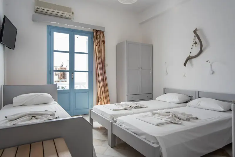Une chambre lumineuse avec deux lits simples et une porte bleue.