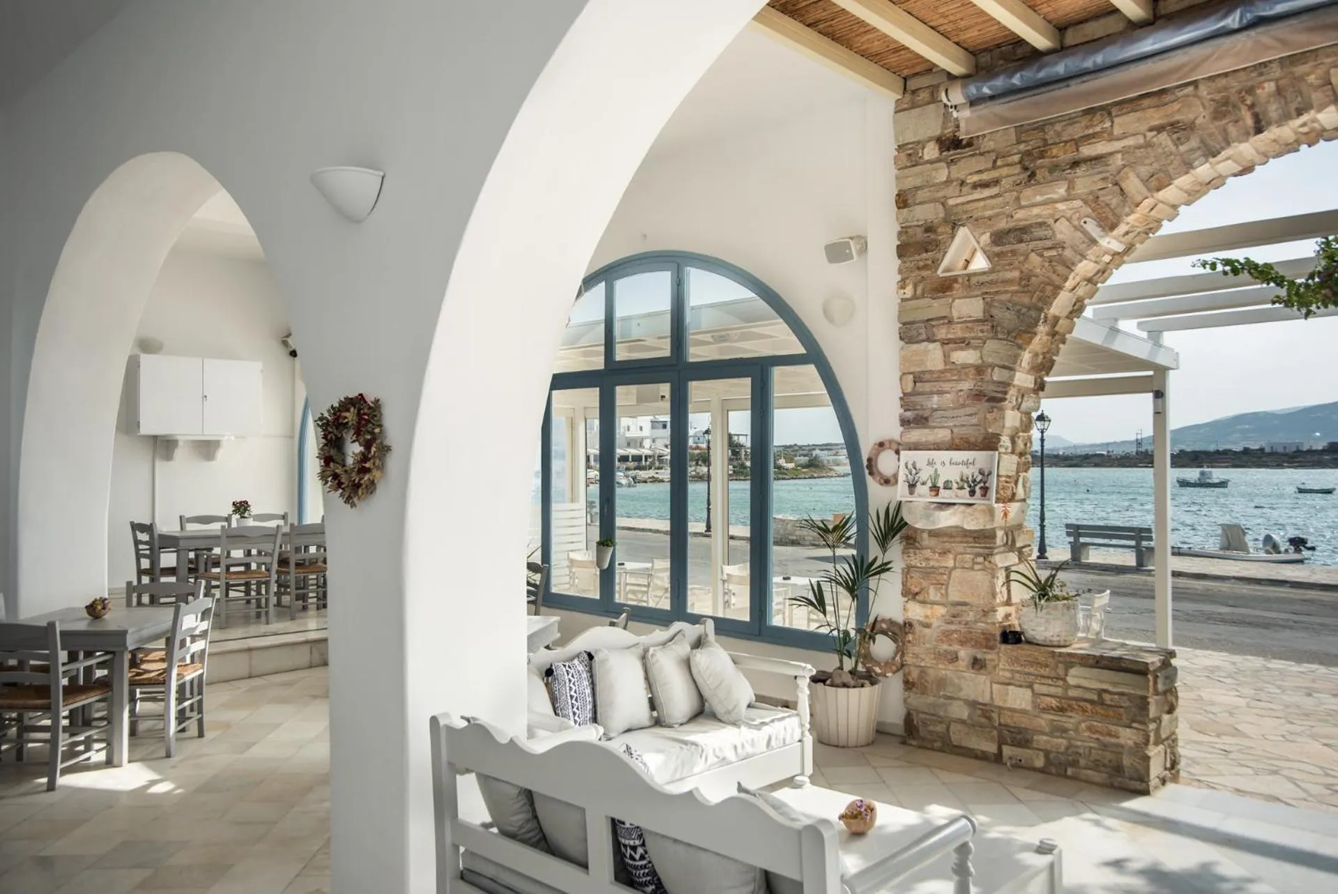 Espace de détente avec canapés blancs et vue sur la mer à travers de grandes baies vitrées.