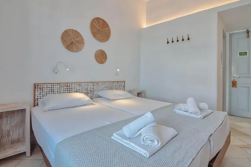 Une chambre lumineuse avec un grand lit recouvert de linge blanc.