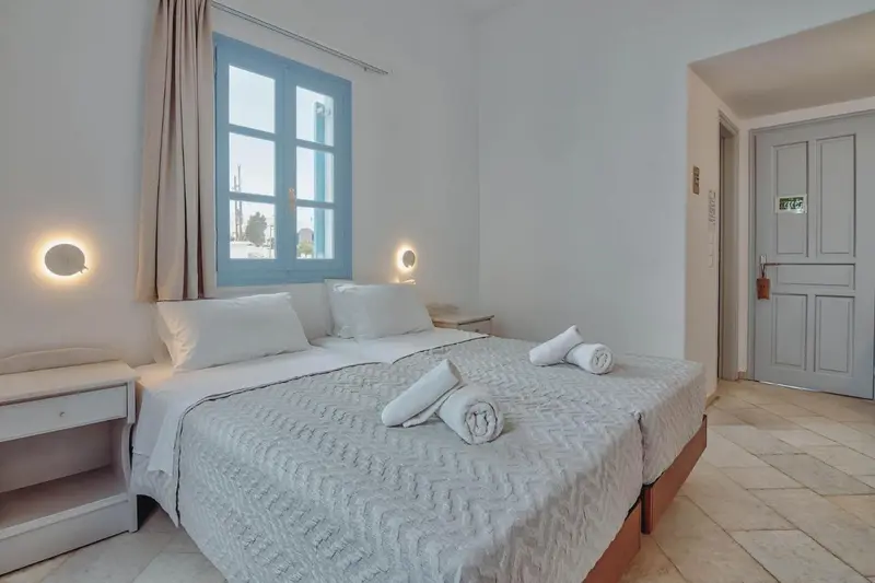 Une chambre lumineuse avec un lit double et une fenêtre bleue.