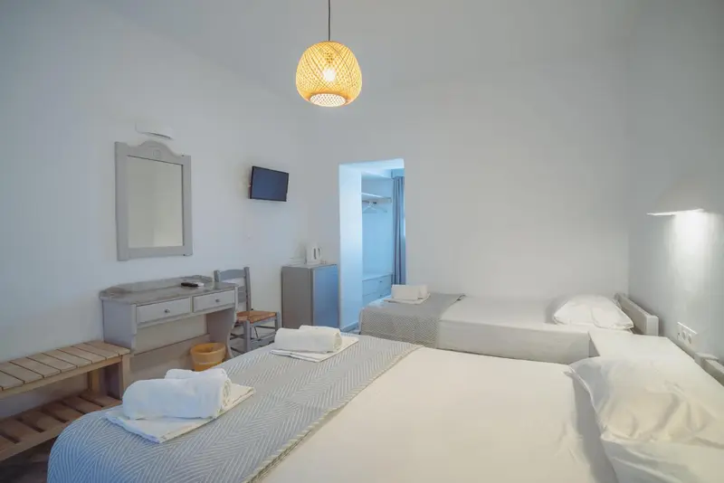 Une chambre lumineuse avec deux lits simples et une coiffeuse.
