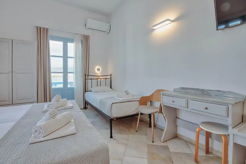 Une chambre lumineuse avec deux lits simples et un bureau.