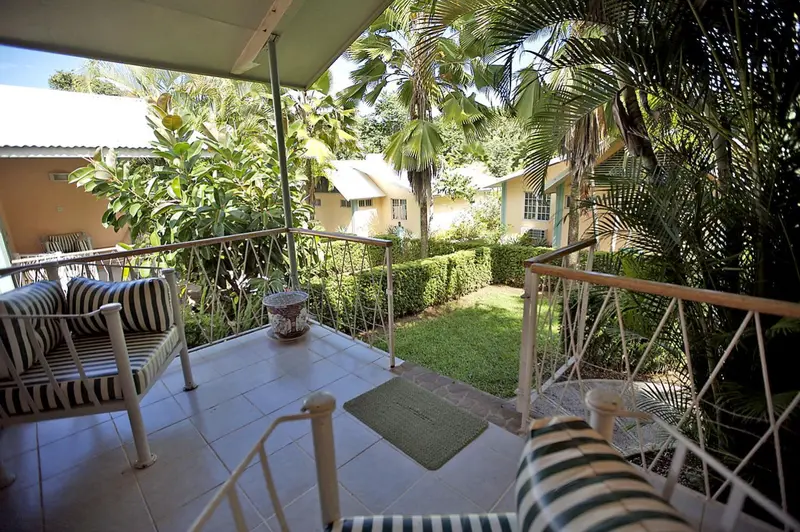 Terrasse ombragée avec mobilier de jardin donnant sur un jardin soigné.