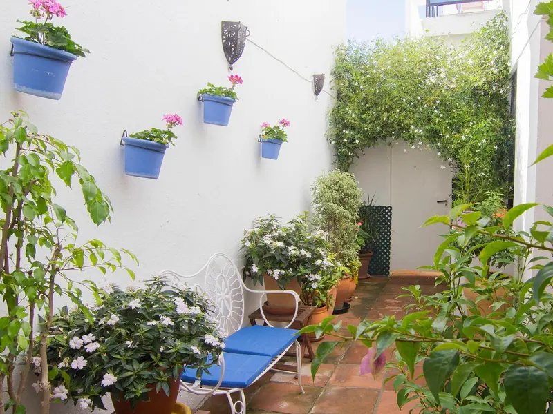 Un espace extérieur fleuri avec une assise en fer forgé.