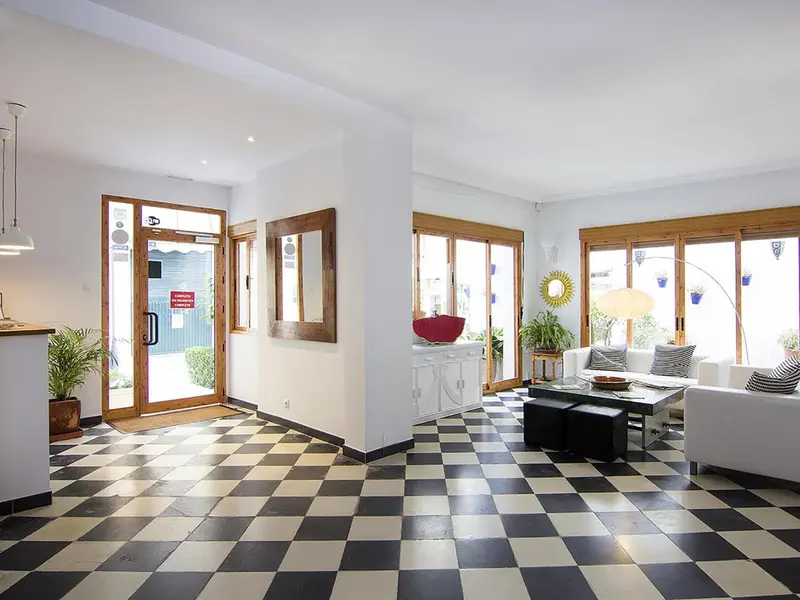 Espace lumineux avec un sol à carreaux noirs et blancs et un canapé blanc.