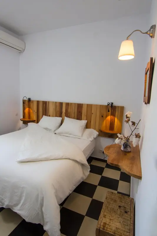Une chambre lumineuse avec un lit recouvert d'une couverture blanche et un sol carrelé noir et blanc.