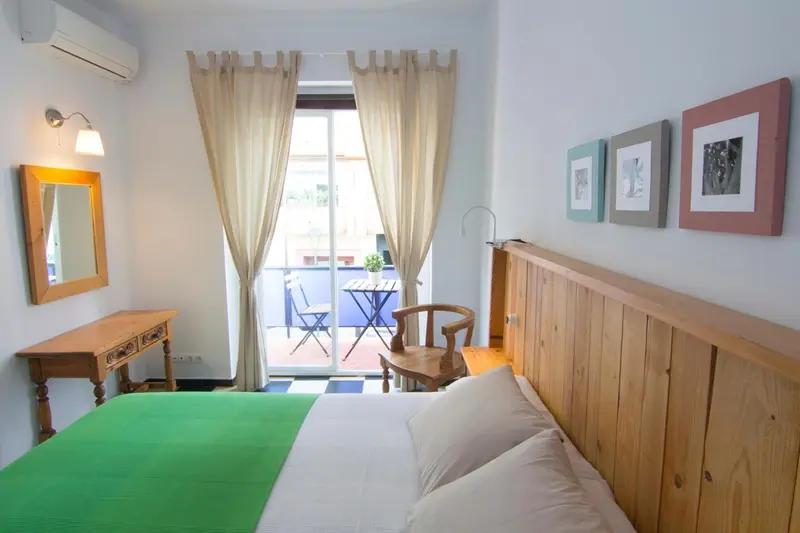 Une chambre lumineuse s'ouvre sur une terrasse avec table et chaises.