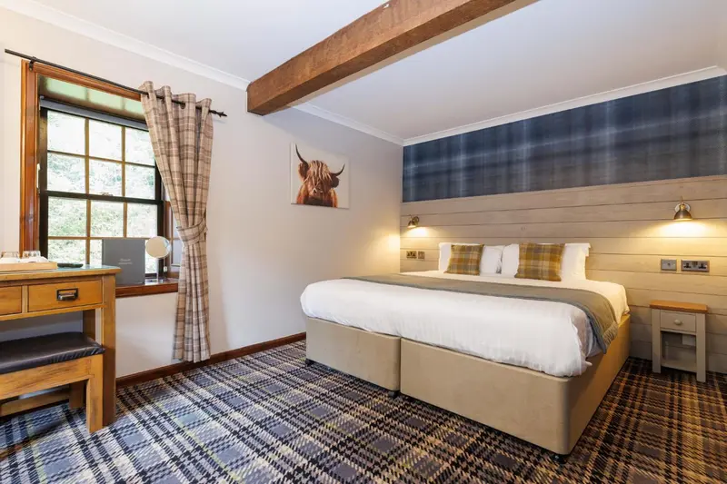 Une chambre d'hotel avec un lit double et une vue sur un paysage boisé.