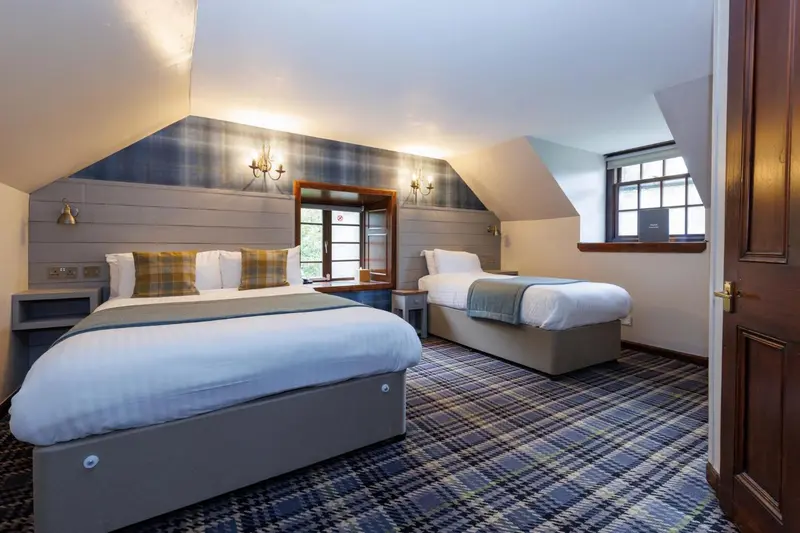 Chambre mansardée avec deux lits et une fenêtre.