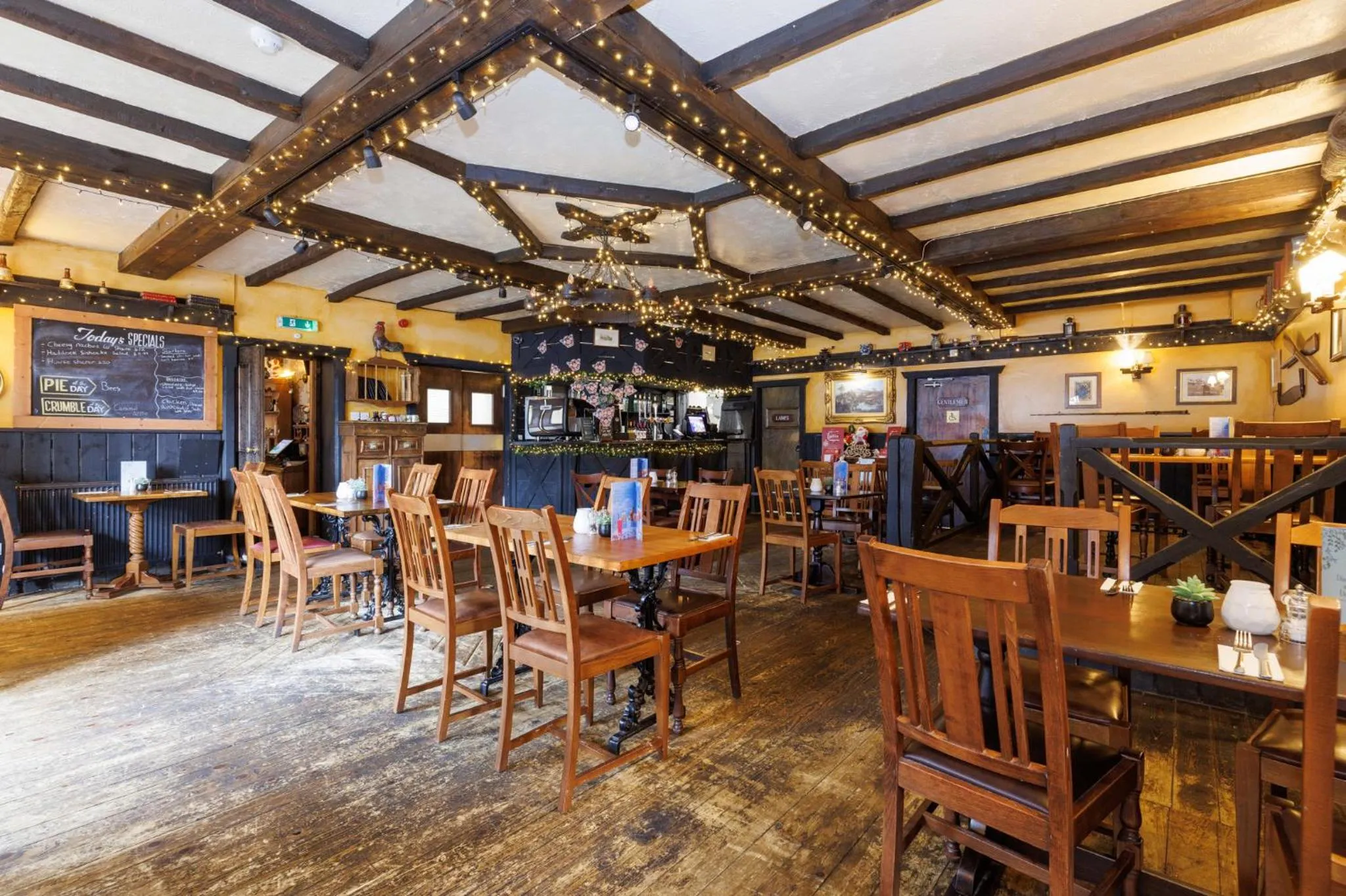 Une salle de restaurant chaleureuse avec des tables en bois et une décoration festive.