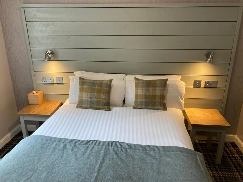 Lit double avec oreillers et couvertures blanches dans une chambre.
