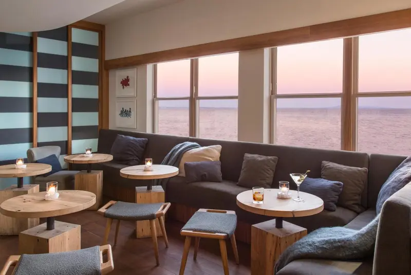 Un espace de détente avec des tables basses et des canapés près d'une grande fenêtre donnant sur la mer.