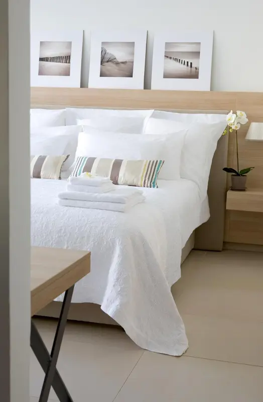 Un lit blanc avec des oreillers et une couverture est dispose dans une chambre claire.