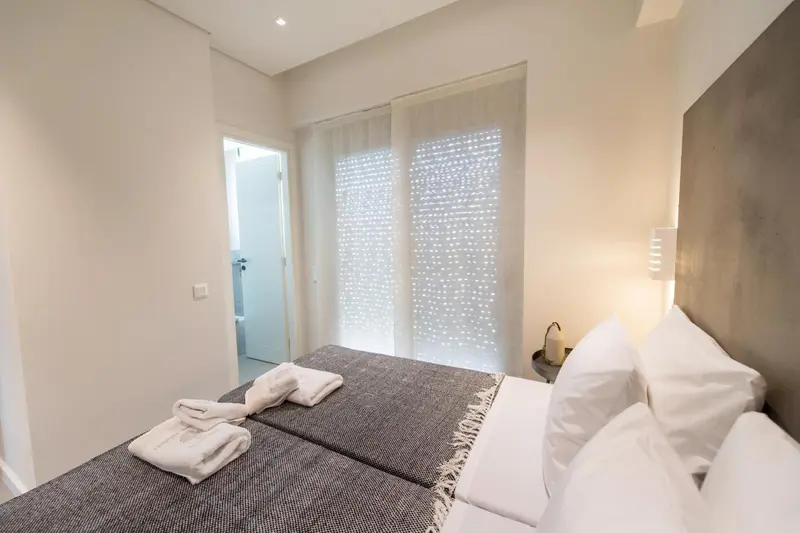 Une chambre lumineuse avec un grand lit et une fenêtre voilée.