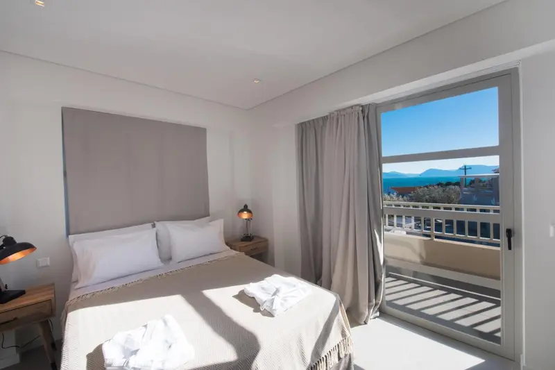 Une chambre lumineuse avec un grand lit donnant sur une vue mer.