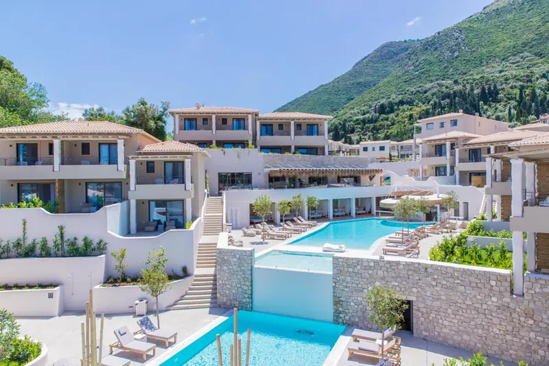 Vue d'un complexe hôtelier blanc avec piscine et végétation luxuriante.